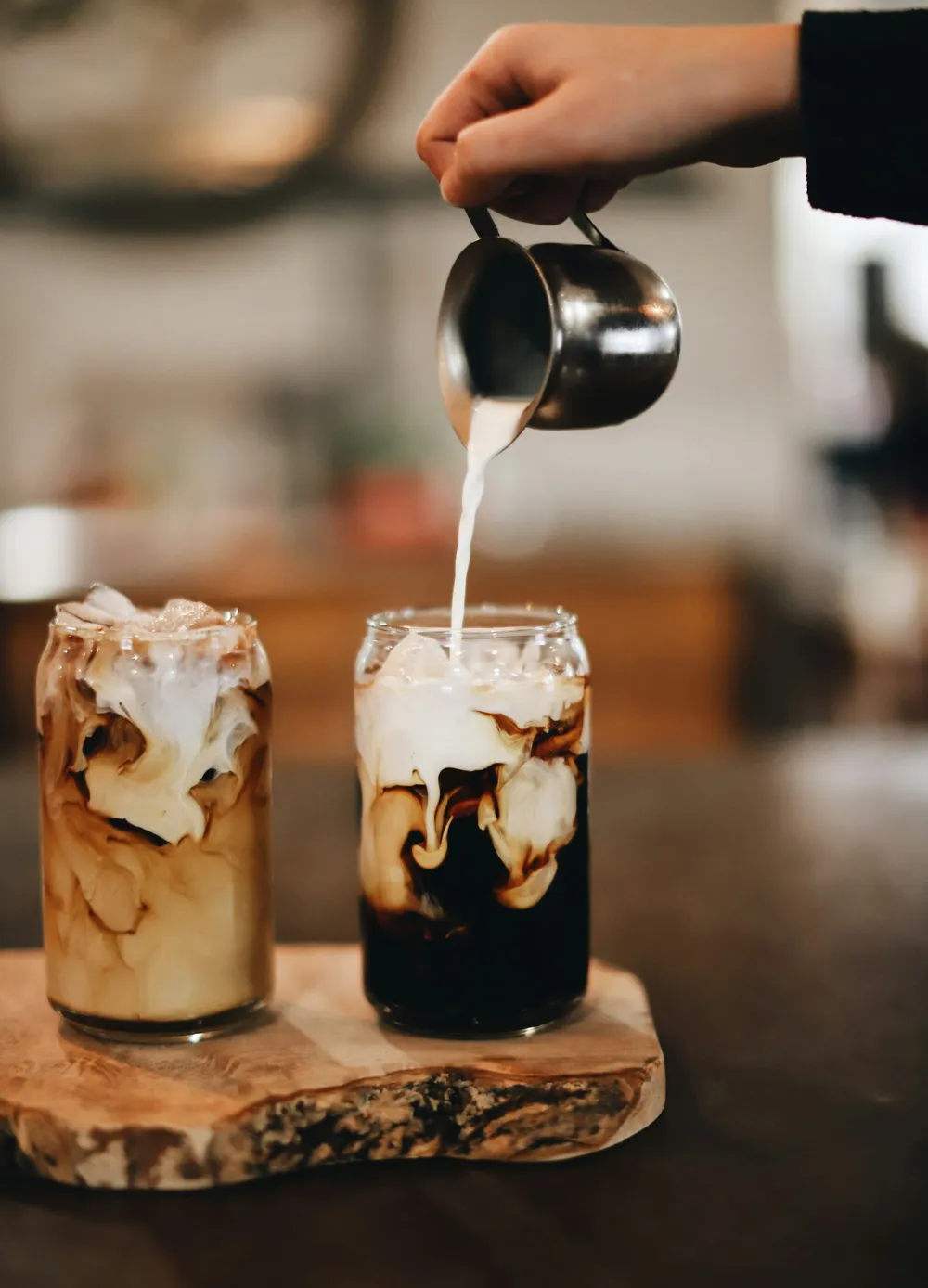 Cream being poured into two glasses of iced coffee